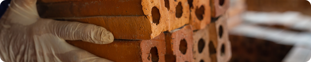 Gloved hand stacking recovered clay bricks